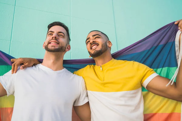 Gay pareja abrazando y mostrando su amor con arco iris bandera. —  Fotos de Stock