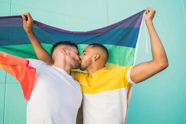 Gay pareja abrazando y mostrando su amor con arco iris bandera. — Foto de Stock