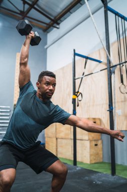 Crossfit sporcu dambılla egzersiz yapıyor.