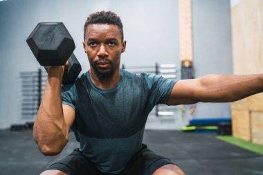 Crossfit sporcu dambılla egzersiz yapıyor.