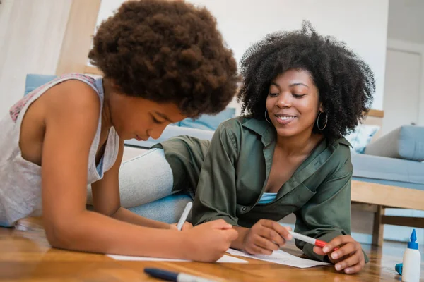 Moeder en zoon tekening met gekleurde potloden op de vloer. — Stockfoto