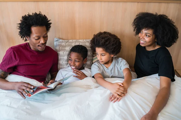 Rodina čte knihu na posteli doma. — Stock fotografie