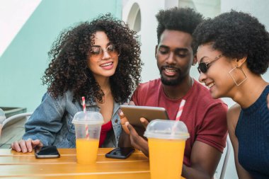 Dijital tablet kullanan üç afro arkadaş.