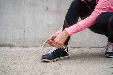 Ayakkabı bağcıklarını bağlayan atletik kadın.