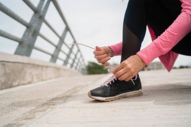 Ayakkabı bağcıklarını bağlayan atletik kadın.