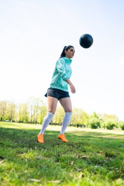 Genç bir kadın topla futbol oynuyor..