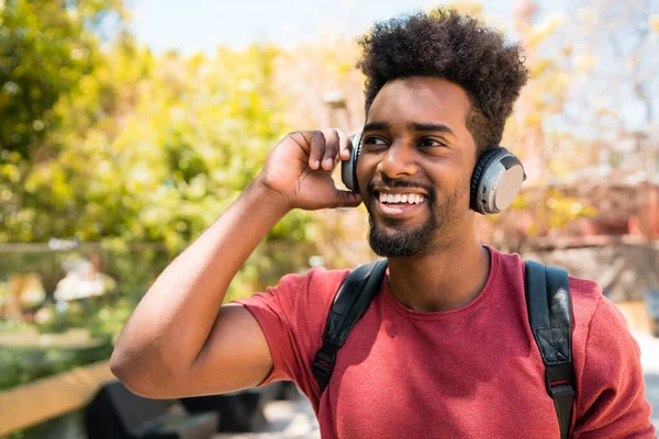 Jonge afro man die naar muziek luistert met een koptelefoon. — Stockfoto