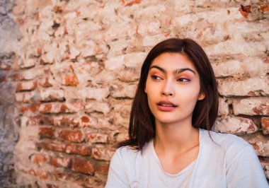 Duvara dayanmış genç Latin kadın.