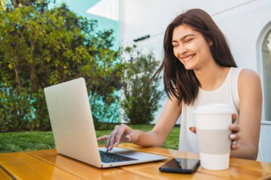 Kahve dükkanında dizüstü bilgisayar kullanan genç bir kadın..