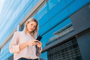 İş kadını cep telefonunu açık havada kullanıyor..