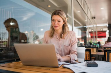 Dizüstü bilgisayarında çalışan genç bir iş kadını..