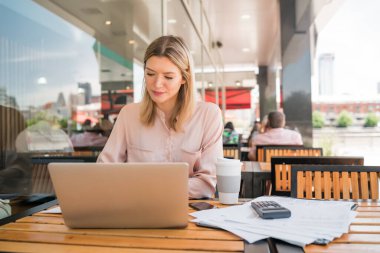 Dizüstü bilgisayarında çalışan genç bir iş kadını..