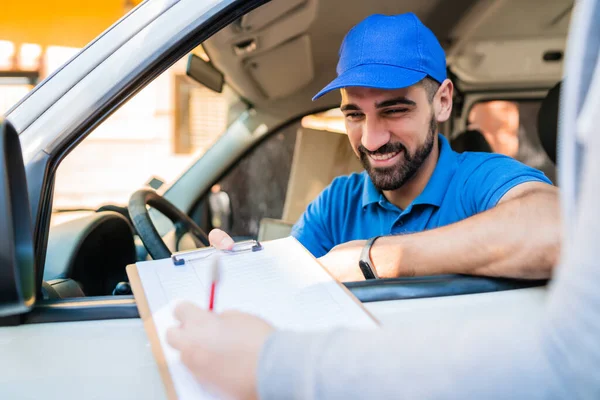 Repartidor en furgoneta mientras el cliente firma en portapapeles. — Foto de Stock