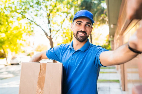Entrega hombre llevando paquetes mientras que hace entrega a domicilio. —  Fotos de Stock
