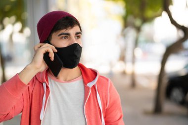 Genç adam dışarıda telefonla konuşuyor..