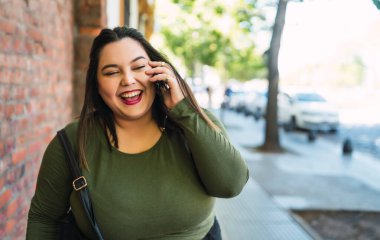 Genç ve iri yarı bir kadın telefonda konuşuyor..