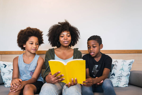 Afro mother reading a book to her children.