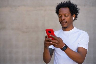 Atletik adam cep telefonunu açık havada kullanıyor..