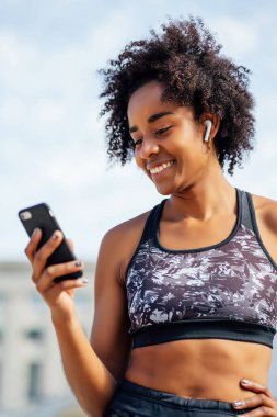 Dışarıda cep telefonunu kullanan atletik bir kadın..