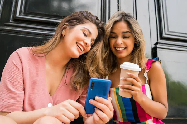 Dışarıda cep telefonu kullanan iki arkadaş..