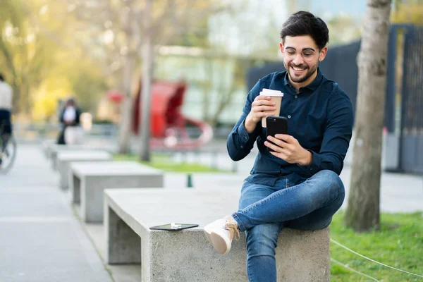 Mladý muž používá svůj mobilní telefon venku. — Stock fotografie