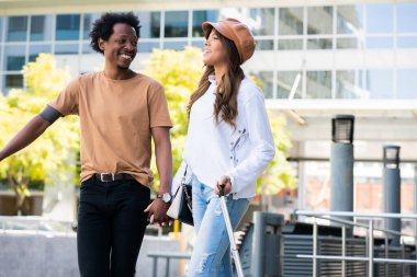 Dışarıda yürürken bavul taşıyan turist çift..