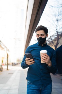 Genç adam cep telefonunu açık havada kullanıyor..