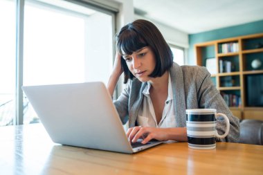 Evden bilgisayarla çalışan bir kadın..