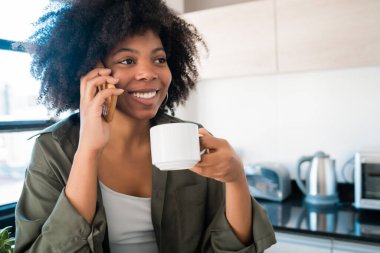 Afro kadın evde telefonla konuşuyor..