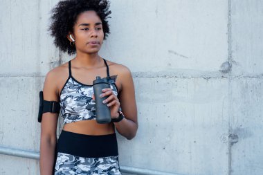 Atletik kadın, işten sonra dışarıda su içiyor..