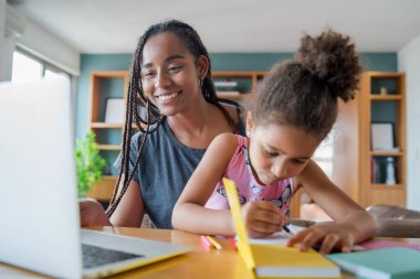 Ev okulunda kızına yardım eden bir anne..