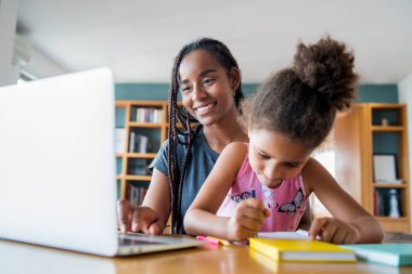 Ev okulunda kızına yardım eden bir anne..