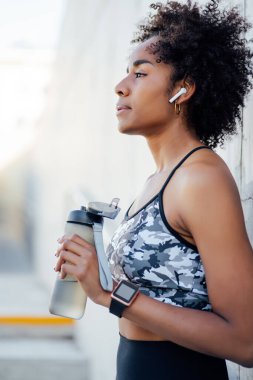 Atletik kadın, işten sonra dışarıda su içiyor..