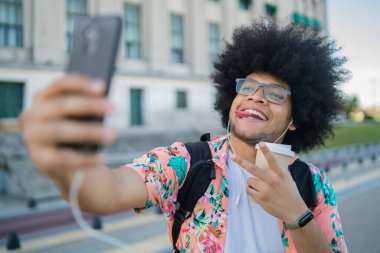 Latin adam dışarıda telefonla selfie çekiyor..