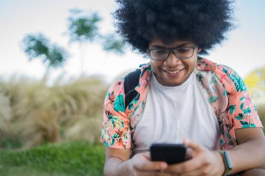 Genç adam cep telefonunu açık havada kullanıyor..