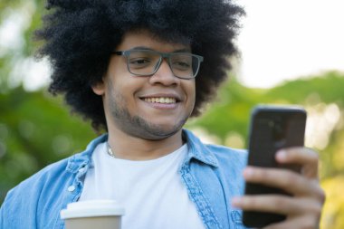 Genç adam cep telefonunu açık havada kullanıyor..