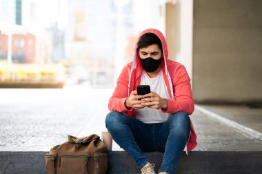 Genç adam cep telefonunu açık havada kullanıyor..