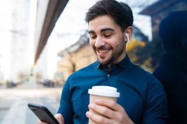 Genç adam cep telefonunu açık havada kullanıyor..