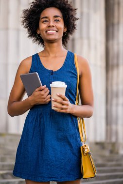 Elinde dijital tablet ve kahve tutan bir iş kadını..