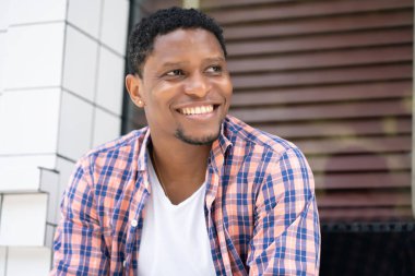 Afro-Amerikalı bir adam mağazanın vitrininde oturuyor..