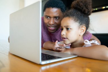 Bir baba kızına ev okulunda yardım ediyor..