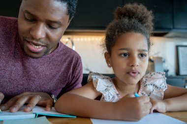 Bir baba kızına ev okulunda yardım ediyor..