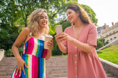 Dışarıda cep telefonu kullanan iki arkadaş..