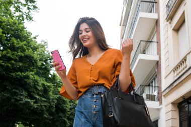 Cep telefonunu kullanan genç bir kadın..