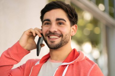 Genç adam dışarıda telefonla konuşuyor..