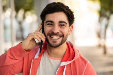 Genç adam dışarıda telefonla konuşuyor..