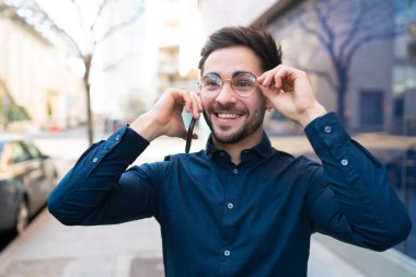 Genç adam dışarıda telefonla konuşuyor..