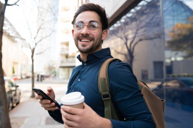 Genç adam cep telefonunu açık havada kullanıyor..