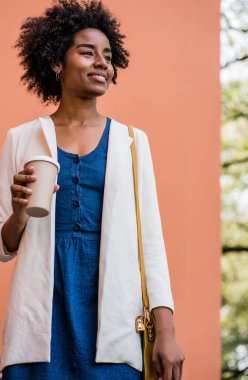 Afro iş kadını elinde bir fincan kahve tutuyor..