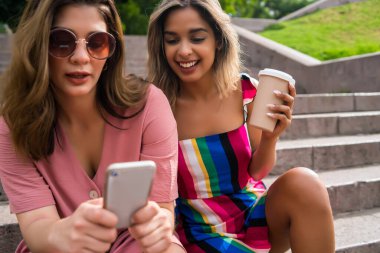 Dışarıda cep telefonu kullanan iki arkadaş..